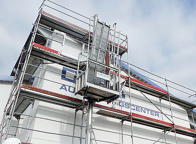 Ein Baugerüst mit einem Aufzug bewegt sich an der Fassade eines Gebäudes.