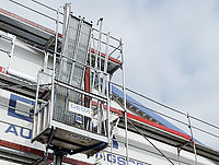 Ein Baugerüst mit einem Aufzug bewegt sich an der Fassade eines Gebäudes.