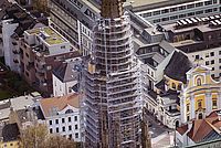 Ein Kirchturm wird von Baugerüsten umgeben und Arbeiter sind daran tätig.