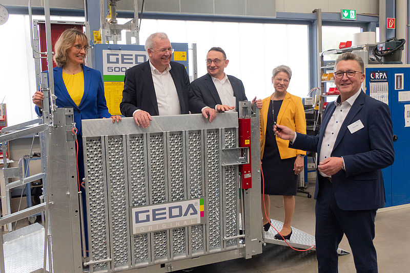 Fünf Personen stehen um eine GEDA-Maschine herum.