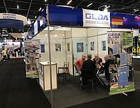 Messestand mit vier Personen, die an einem Tisch sitzen und diskutieren.