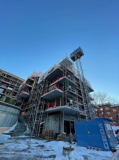 Mehrstöckiges Gebäude im Bau, von Gerüsten umgeben im Winter unter blauem Himmel.
